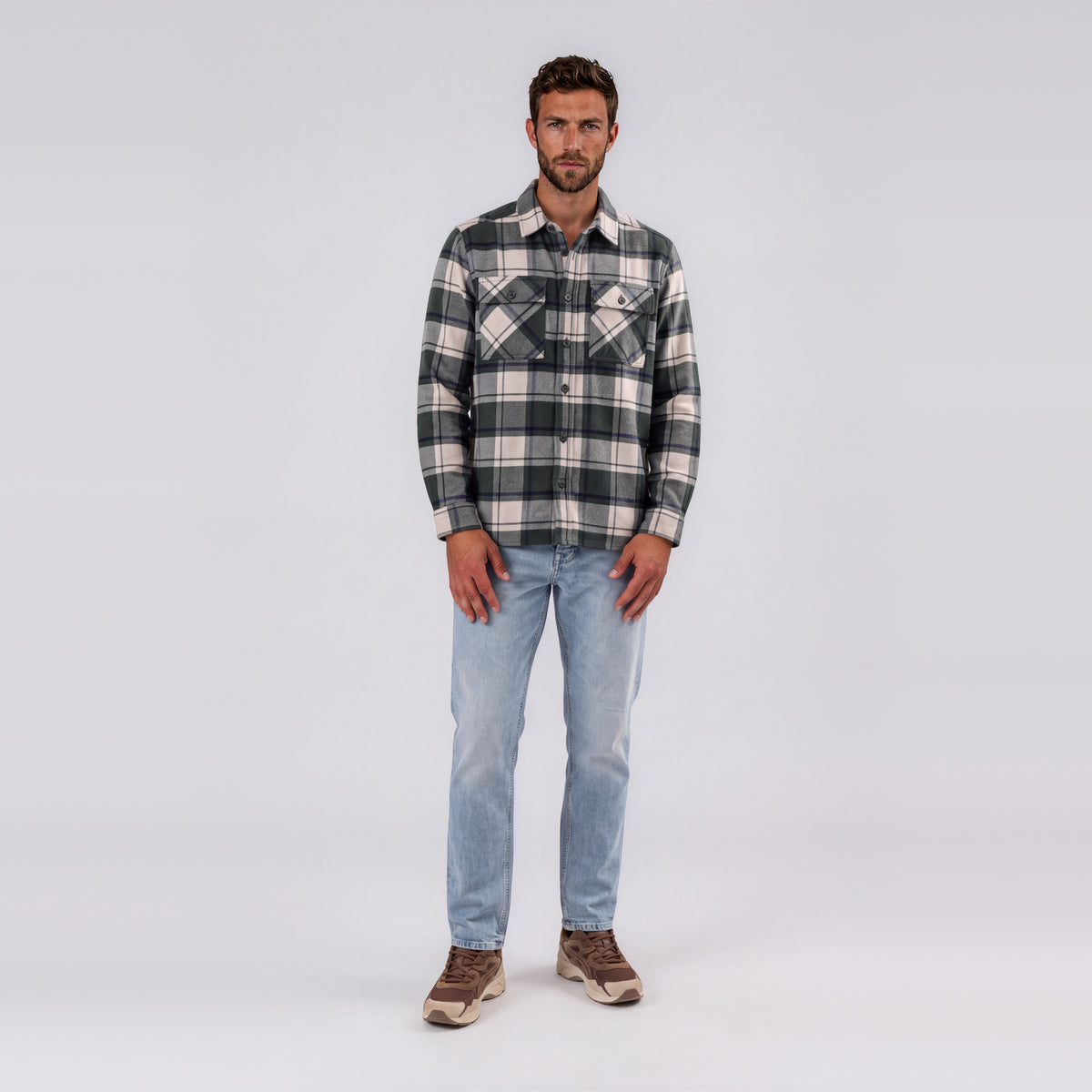 Man wearing Garment Works Esco cream and green check two pocket overshirt with light wash jeans