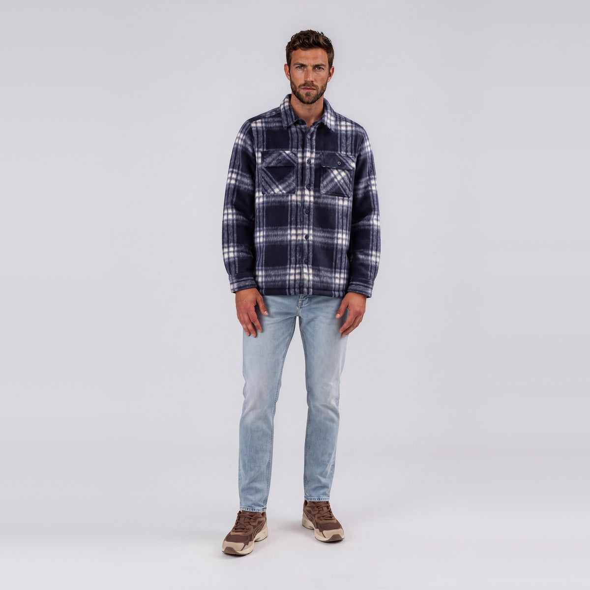 Man wearing Garment Works Esco navy check two pocket overshirt with light wash jeans